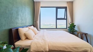 Een slaapkamer met een groot bed, uitzicht door een raam en een kamerplant.