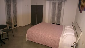 Quarto com cama, cadeira, guarda-roupa e escrivaninha.