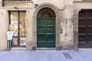 A green door with a decorative arch above it, a small balcony with a railing, and a sign above the door. - Santo Spirito Nest - Florence (Firenze)