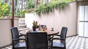 A round table with four chairs, a potted plant, and a coffee maker on a checkered floor. - Semi-detached house in green setting (Lignano Sabbiadoro)