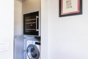 Un espace buanderie compact comprenant un lave-linge et un four à micro-ondes placé au-dessus.