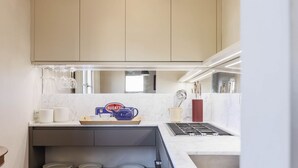 Eine moderne Küche mit beigen Schränken, einer Arbeitsfläche mit einer Bugatti-Kaffeemaschine und einem Spülbecken.