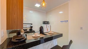 A compact kitchen with a microwave, refrigerator, coffee maker, and a sink. - Condomíno American Praia  (Porto Seguro)