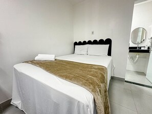 Une chambre d’hôtel avec un lit, une salle de bain avec un miroir et une serviette sur le lit.