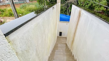 Uma escada estreita leva a uma área pequena coberta por um toldo azul.