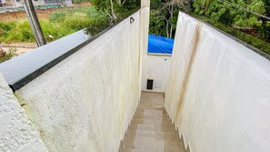 A narrow stairway leading to a small enclosed area with a blue tarp roof. - Condomíno American Praia  (Porto Seguro)