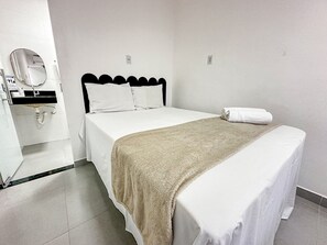 A hotel room with a bed, a bathroom with a sink, and a mirror. - Condomíno American Praia  (Porto Seguro)