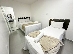 A hotel room with two beds, a bathroom, and a mirror. - Condomíno American Praia  (Porto Seguro)