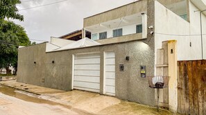 Un edificio de dos pisos con una puerta de garaje, un balcón pequeño y una cámara de seguridad.