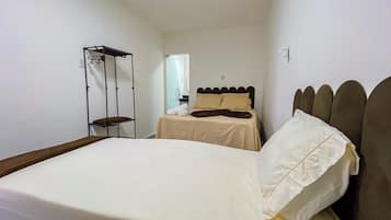 Um quarto pequeno e bem arrumado com uma cama de solteiro, uma mesinha de cabeceira e um guarda-roupa.