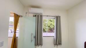 A room with a window, grey curtains, a door, and an air conditioning unit. - Condomíno American Praia (Porto Seguro)