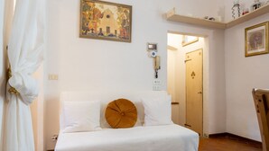 Quarto de hotel com cama, quadro na parede, telefone e porta para outro cômodo.