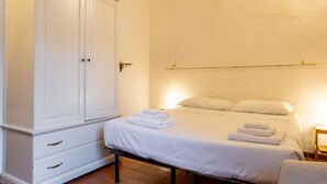 Quarto com cama, guarda-roupa e mesa de cabeceira.