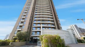 A tall, modern building with multiple balconies, a curved facade, and a clear sky. - Vogue | Siraj Tower Arjan near Miracle Garden (Dubai)