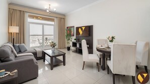 A modern living room with a sofa, a coffee table, and a dining area with chairs and a table. - Vogue | Siraj Tower Arjan near Miracle Garden (Dubai)