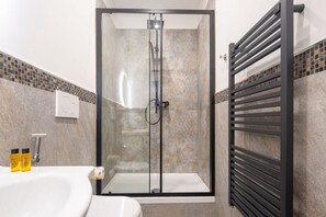 A modern bathroom with a glass-enclosed shower, a white sink, and a black towel rack. - San Frediano Central Studio (Florence)