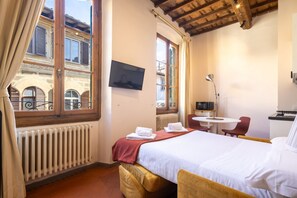 Ein Hotelzimmer mit Bett, Fernseher, kleinem Tisch und Stuhl.
