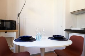 Ein runder Esstisch mit blauen Schüsseln und Gläsern, umgeben von roten Stühlen, in einer modernen Küche.