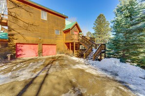Ein Holzhaus mit einer roten Garage, einer Holztreppe und einer verschneiten Auffahrt.
