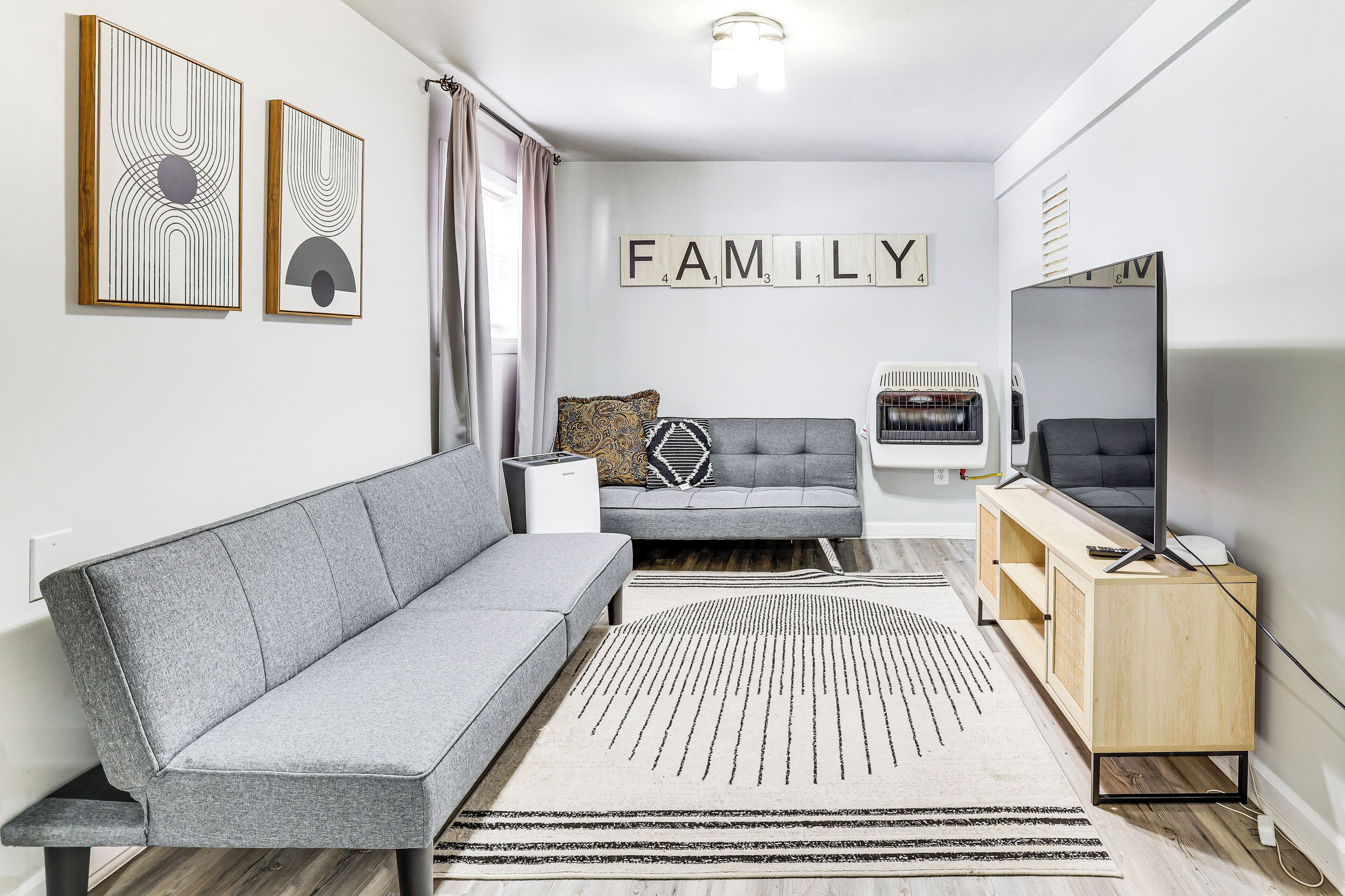 A modern living room with a grey sofa, a wooden cabinet, and a TV.