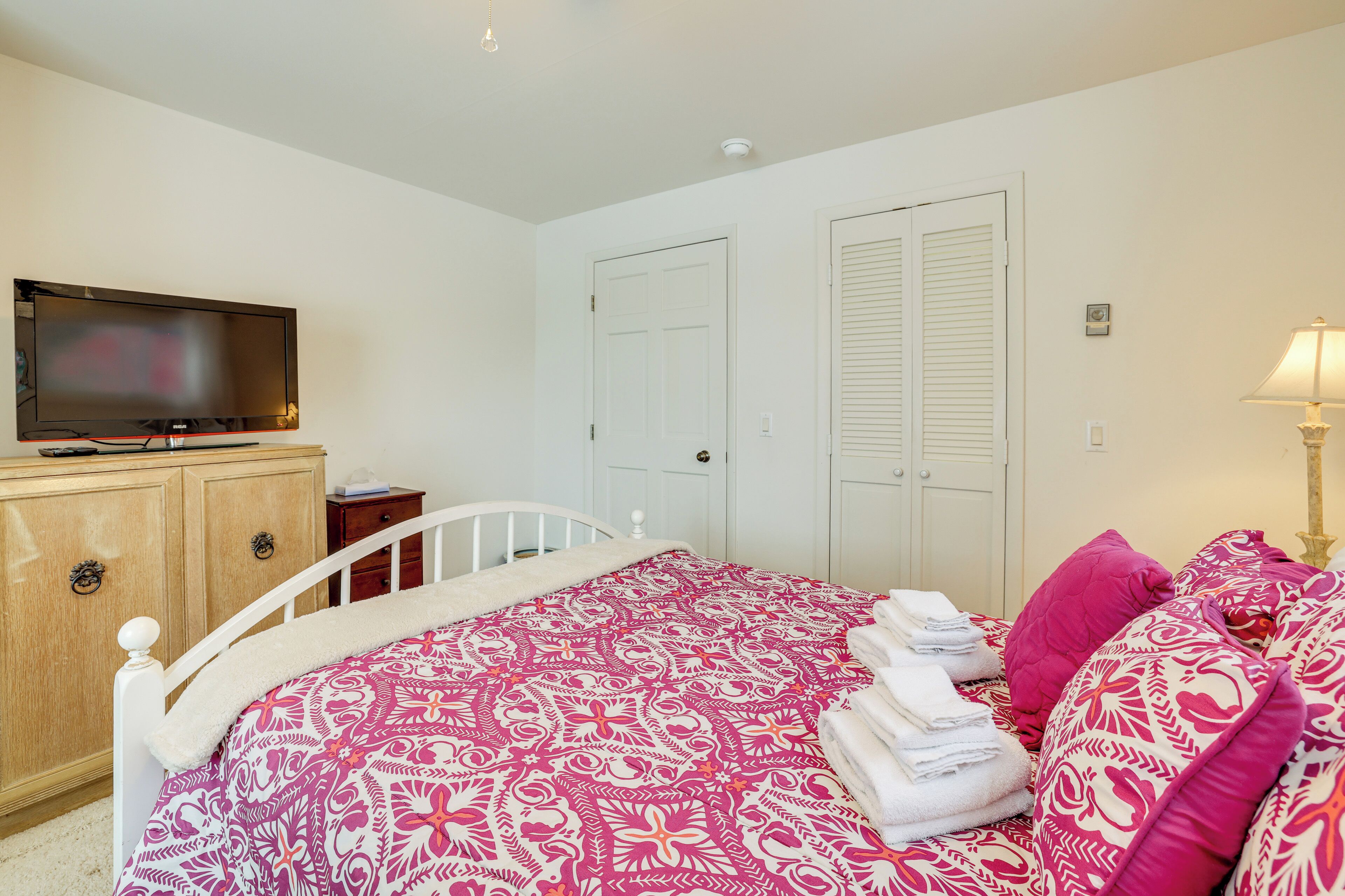 A bedroom with a bed, a television, a wardrobe, and a lamp.