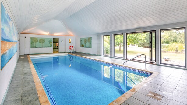 An indoor swimming pool with clear glass walls, a tiled floor, and a ceiling with wooden panels. - Cherry Cottage  Luxury for Couples, Private Use of Indoor Heated Swimming Pool (Faversham)