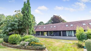 A modern building with a sloped roof and multiple windows. - Cherry Cottage  Luxury for Couples, Private Use of Indoor Heated Swimming Pool (Faversham)