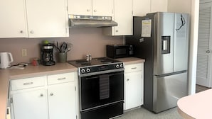 A kitchen with white cabinets, a stainless steel refrigerator, a microwave, a stove, and a coffee maker. - NEW LISTING! Rehoboth by the Sea - Ocean Block - 19 Cullen St (Dewey Beach)