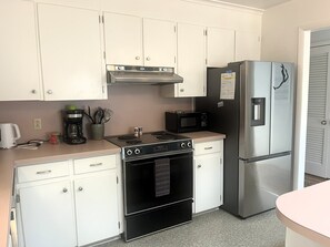 A kitchen with white cabinets, a stainless steel refrigerator, a microwave, a stove, and a coffee maker. - NEW LISTING! Rehoboth by the Sea - Ocean Block - 19 Cullen St (Dewey Beach)