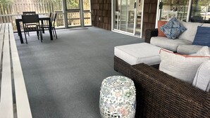 A covered patio area with a wicker sofa, a patterned ottoman, and a dining table with chairs. - NEW LISTING! Rehoboth by the Sea - Ocean Block - 19 Cullen St (Dewey Beach)