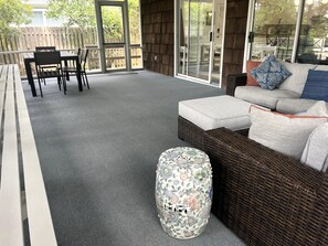 A covered patio area with a wicker sofa, a patterned ottoman, and a dining table with chairs. - NEW LISTING! Rehoboth by the Sea - Ocean Block - 19 Cullen St (Dewey Beach)