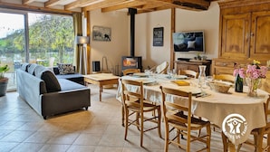 Un salon chaleureux avec un canapé, une table à manger pour quatre personnes, un téléviseur et une cheminée.