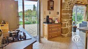 Une cuisine équipée d’une cuisinière, d’une machine à café et d’une arche en pierre.