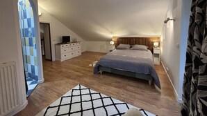 A bedroom with a sloped ceiling, a bed with a wooden headboard, a dresser, and a TV on top. - Tranquil cottage with SPA, garden and pond, pets allowed for 6 guests (Bézenet)