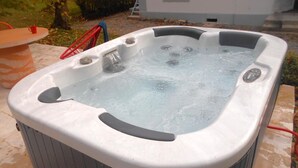 A hot tub with a control panel and a faucet, surrounded by a patio area with a table and chairs. - Tranquil cottage with SPA, garden and pond, pets allowed for 6 guests (Bézenet)