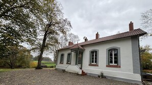 A two-story house with a gravel driveway, a large tree to the left, and a view of the countryside. - Tranquil cottage with SPA, garden and pond, pets allowed for 6 guests (Bézenet)