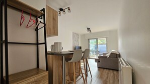 Une cuisine moderne dotée d’un plan de travail en bois, d’une machine à café et d’un coin repas avec un canapé et des chaises gris.