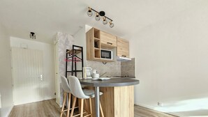 Une cuisine moderne avec un îlot central en bois, des tabourets de bar, un four à micro-ondes et un luminaire suspendu.