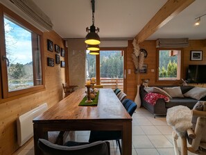 Ein Holzinnenraum mit einem Esstisch, Stühlen, einer Couch und einem Fernseher.