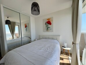 Ein Hotelzimmer mit einem großen Bett, einem Nachttisch, einem Spiegel und einem Blumenbild.
