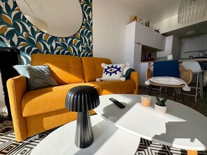 Ein modernes Wohnzimmer mit einem senffarbenen Sofa, einem weißen Couchtisch und einer schwarzen Vase.