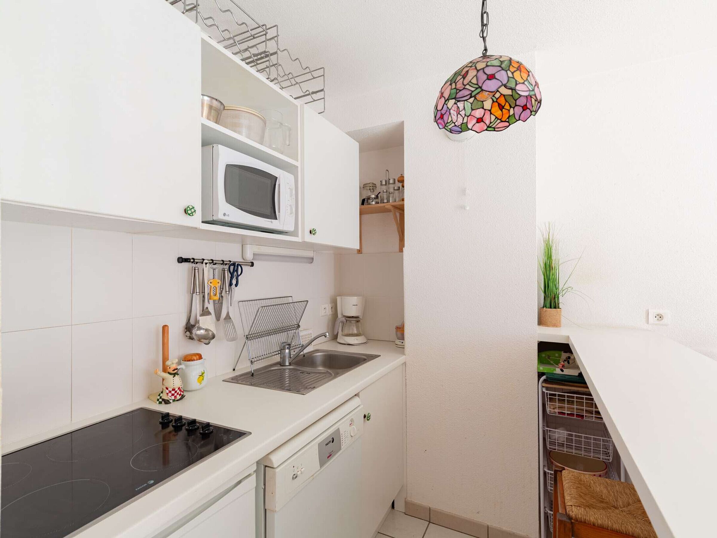 A compact kitchen with white cabinets, a microwave, a sink, and a stove.
