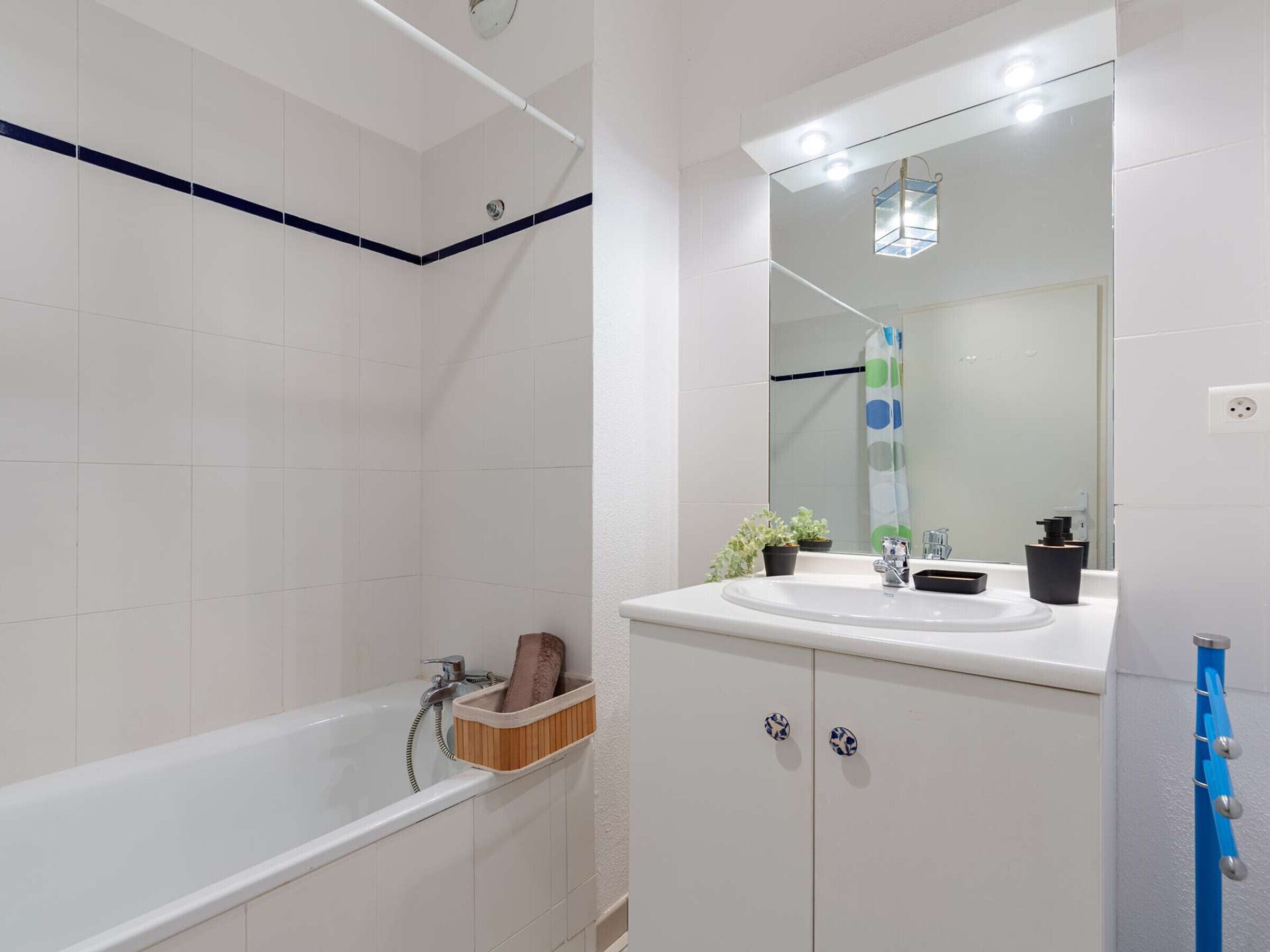 Een moderne badkamer met een bad, een wastafel met spiegel en een douchegordijn.