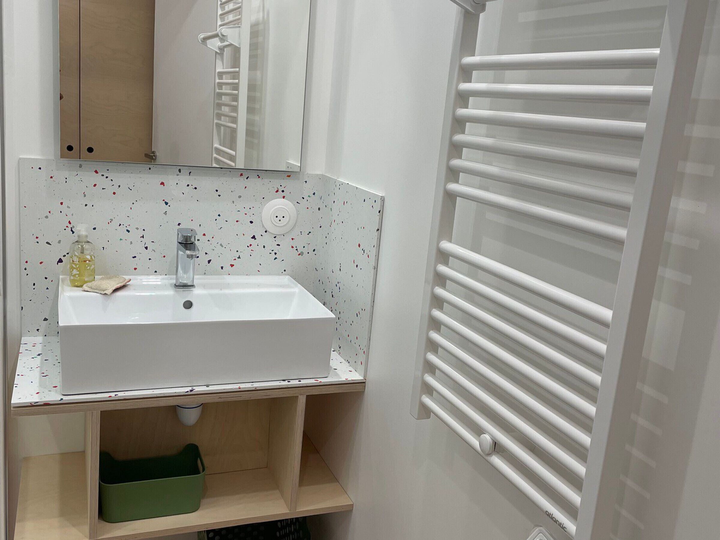 A bathroom with a white sink, a mirror, a towel, and a towel rack.