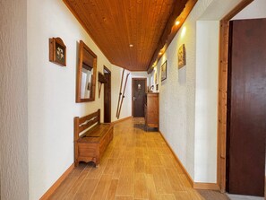 Ein hölzerner Flur mit einer Bank, Holztüren und gerahmten Bildern an den Wänden.