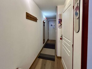A narrow hallway with a wooden floor, a coat rack, and a door with a poster. - Studio cabin for 3 near slopes with parking La Salle-les-Alpes (La Salle-les-Alpes)