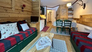 Interior acolhedor de uma cabana de madeira, com um sofá, uma mesa de jantar e uma cozinha.