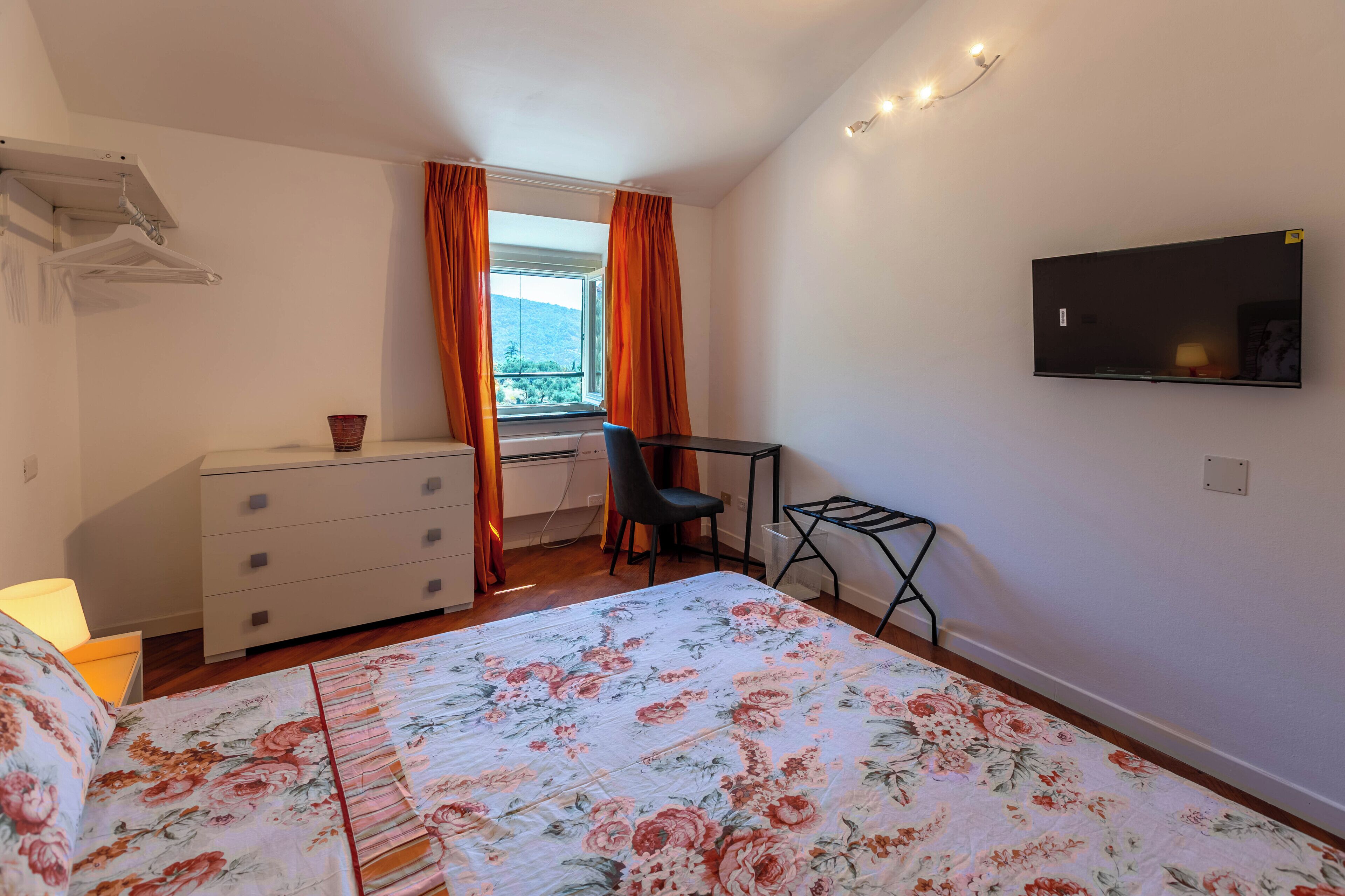 Une chambre à coucher avec un lit, une commode, un bureau et un téléviseur.