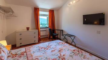 Une chambre à coucher avec un lit, une commode, un bureau et un téléviseur.