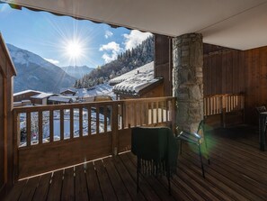 Un pontile in legno con un pilastro in pietra, una panchina e vista su un paesaggio montano innevato.